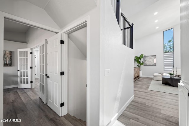 corridor with hardwood / wood-style flooring, lofted ceiling, and french doors