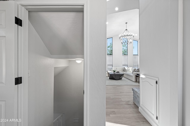 hallway featuring a notable chandelier and light wood-type flooring