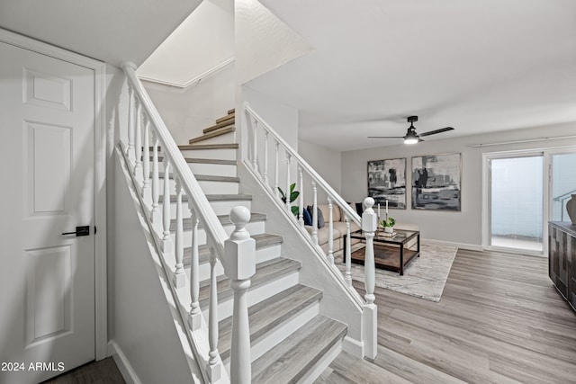 stairway with hardwood / wood-style floors and ceiling fan