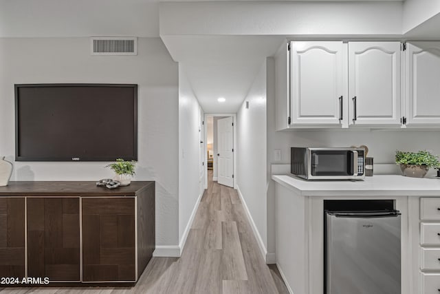 kitchen with appliances with stainless steel finishes, light wood-type flooring, and white cabinetry