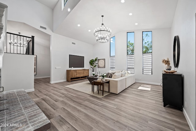 living room featuring a notable chandelier, light wood-type flooring, and high vaulted ceiling