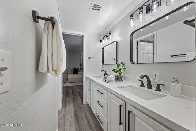 bathroom featuring hardwood / wood-style flooring, vanity, and a textured ceiling