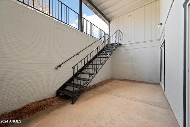 staircase featuring brick wall, concrete floors, and a high ceiling