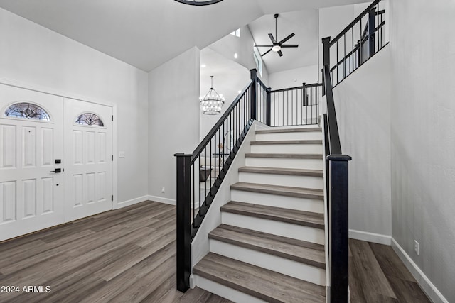 entryway with hardwood / wood-style flooring, ceiling fan with notable chandelier, and lofted ceiling