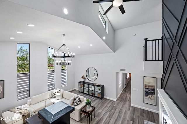 living room with ceiling fan with notable chandelier, hardwood / wood-style flooring, and lofted ceiling