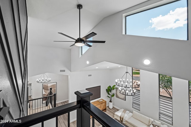 corridor featuring a wealth of natural light, hardwood / wood-style floors, high vaulted ceiling, and an inviting chandelier