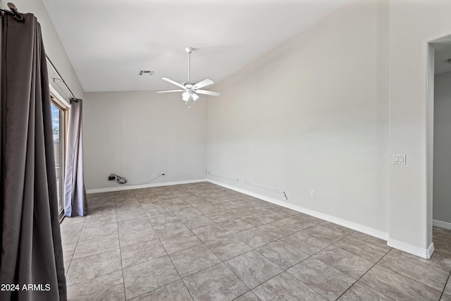 spare room with ceiling fan, lofted ceiling, and light tile patterned floors