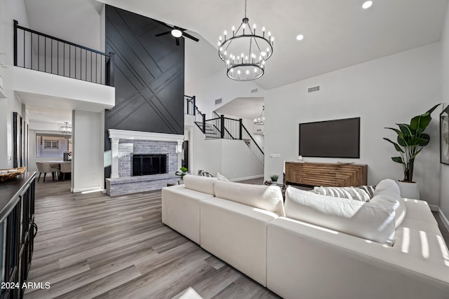 living room with a fireplace, a towering ceiling, light hardwood / wood-style flooring, and ceiling fan