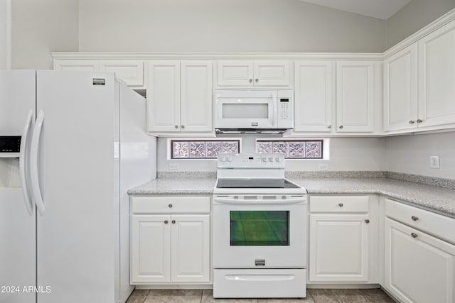 kitchen featuring white cabinets, lofted ceiling, white appliances, and light tile patterned floors