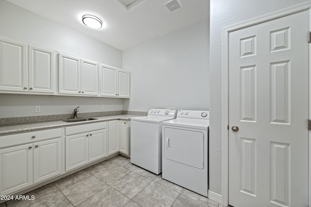 laundry area featuring cabinets, light tile patterned floors, sink, and washing machine and clothes dryer