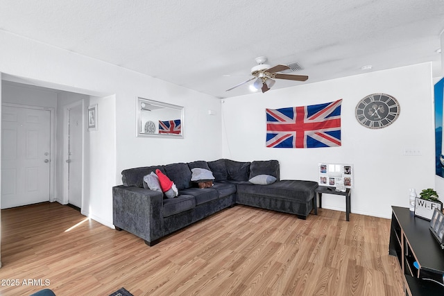 living room featuring ceiling fan, hardwood / wood-style floors, and a textured ceiling