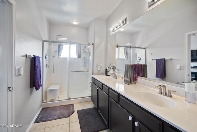 bathroom featuring double vanity, a stall shower, baseboards, tile patterned flooring, and a sink