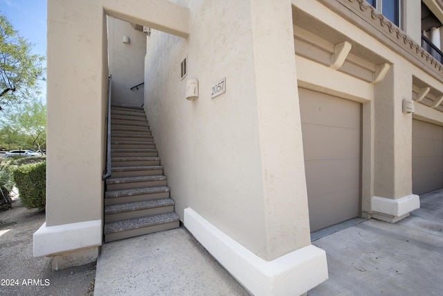 doorway to property featuring a garage, visible vents, and stucco siding