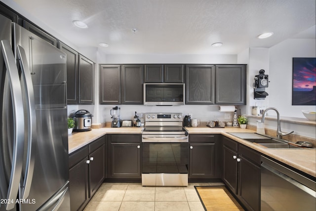 kitchen featuring light tile patterned flooring, stainless steel appliances, light countertops, a sink, and recessed lighting