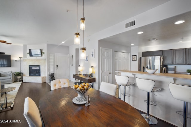 dining area with recessed lighting, visible vents, dark wood finished floors, and a tiled fireplace