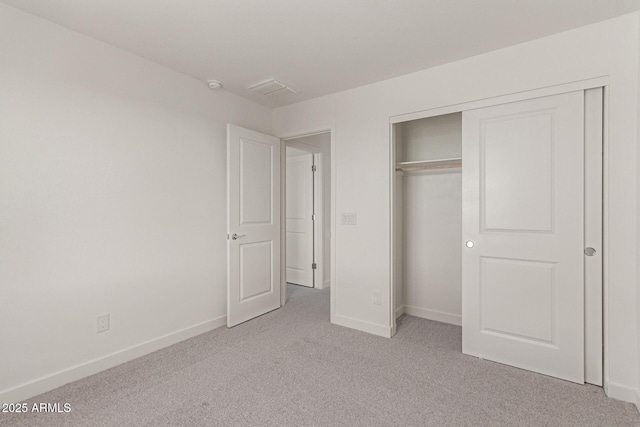 unfurnished bedroom featuring light carpet and a closet