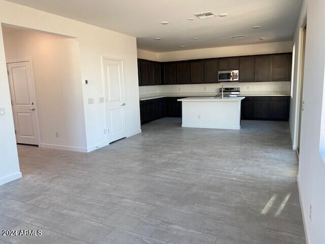 kitchen with a center island with sink, dark brown cabinets, and stainless steel appliances