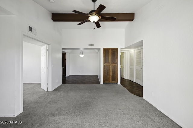 unfurnished bedroom featuring dark colored carpet, beam ceiling, and visible vents