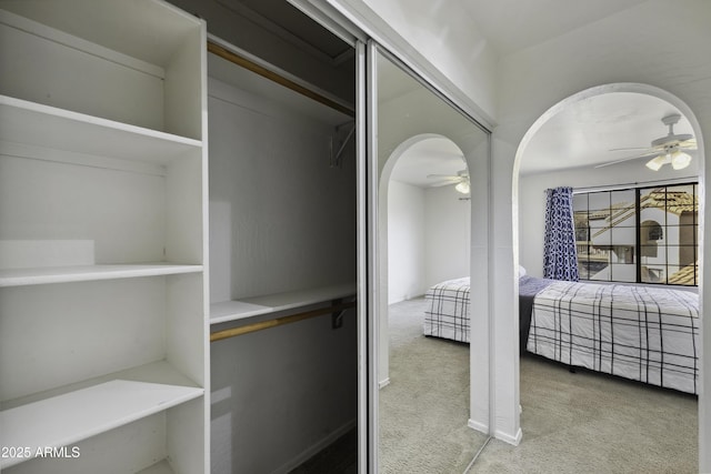 carpeted bedroom with arched walkways and a closet