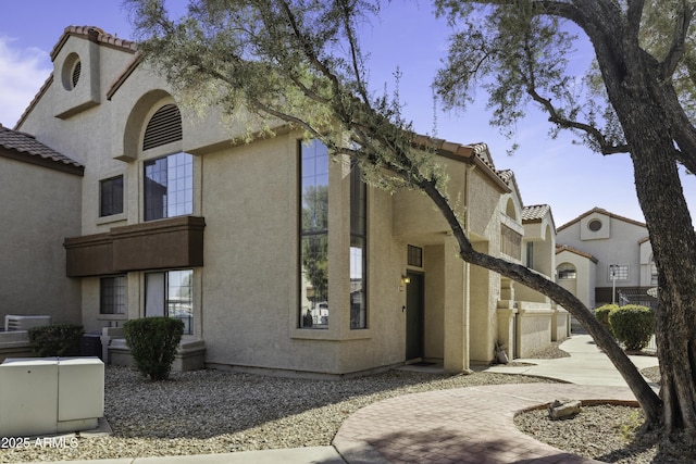 view of property exterior with a tile roof and stucco siding