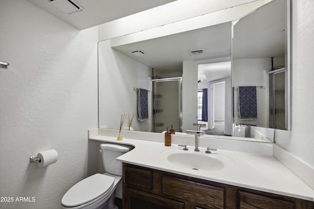 bathroom featuring toilet, vanity, a shower stall, and visible vents