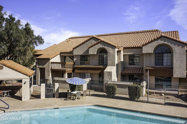 back of property featuring a patio area, fence, a community pool, and stucco siding