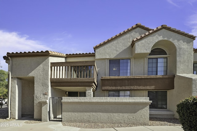 exterior space featuring a balcony, a fenced front yard, a gate, and stucco siding