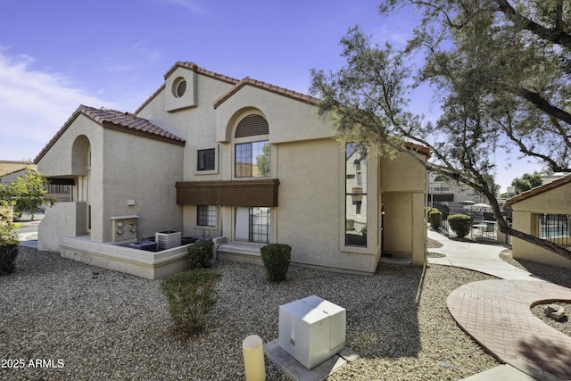 mediterranean / spanish-style home with cooling unit, a tile roof, and stucco siding