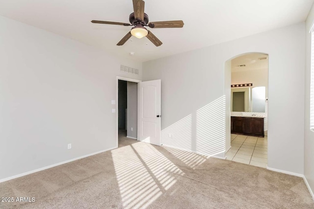 5329 E Harmony Ave, Mesa, AZ 85206 - unfurnished bedroom featuring arched walkways, light colored carpet, baseboards, connected bathroom, and ceiling fan