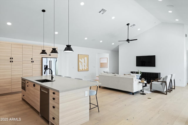 kitchen featuring a sink, visible vents, open floor plan, a center island with sink, and pendant lighting