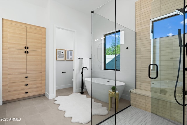 full bath with baseboards, a freestanding tub, a shower stall, and tile patterned floors