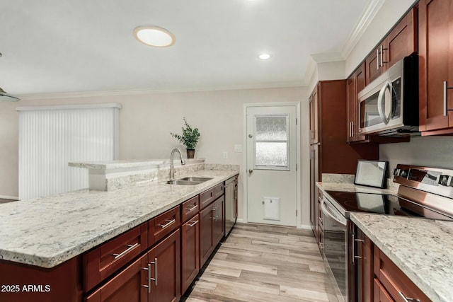 kitchen featuring light wood-style flooring, a sink, appliances with stainless steel finishes, a peninsula, and crown molding