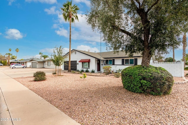 ranch-style house featuring an attached garage, fence, driveway, and a shingled roof