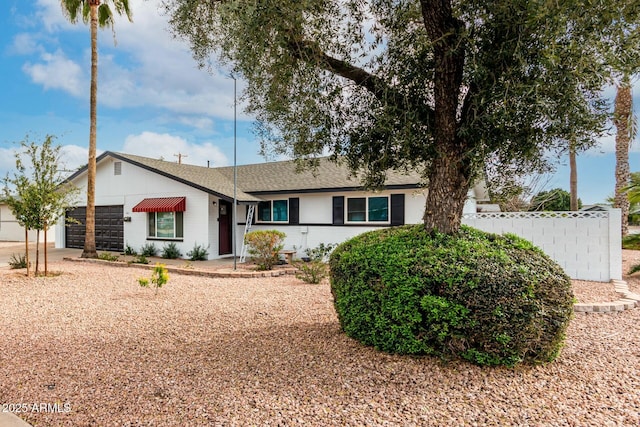 ranch-style house with an attached garage, fence, driveway, and a shingled roof