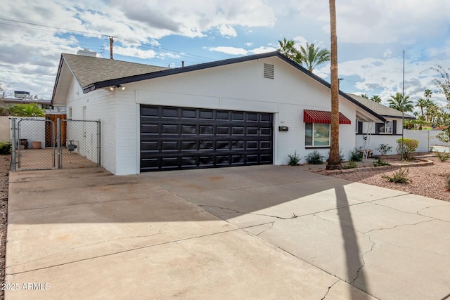 view of front facade featuring a gate, fence, driveway, an attached garage, and brick siding