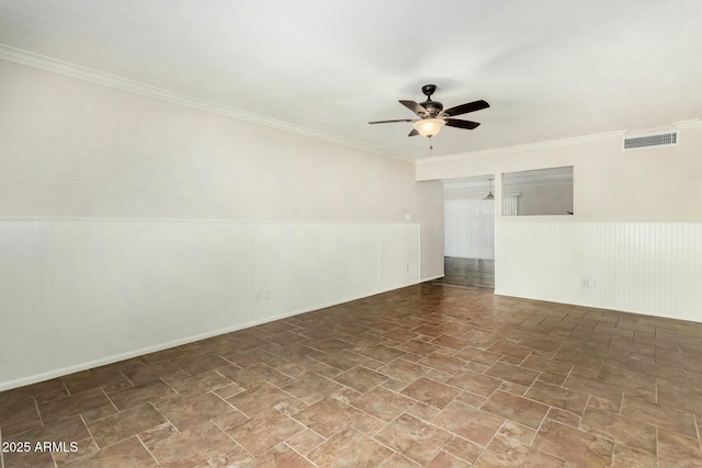 unfurnished room featuring visible vents, crown molding, ceiling fan, and a wainscoted wall