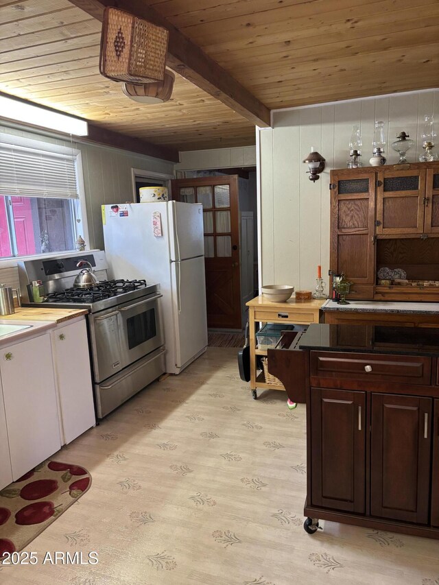 3994 N Mohawk St, Pine, AZ 85544 - kitchen with stainless steel gas range oven, wooden ceiling with exposed beams, light wood-type flooring, freestanding refrigerator, and wood walls