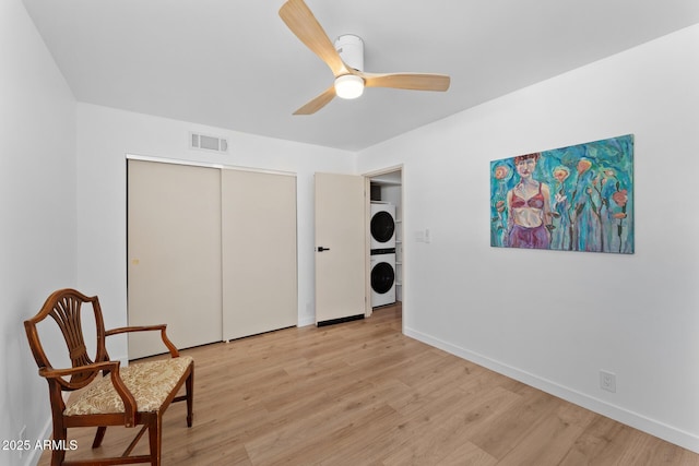 sitting room featuring ceiling fan, light hardwood / wood-style flooring, and stacked washer and dryer