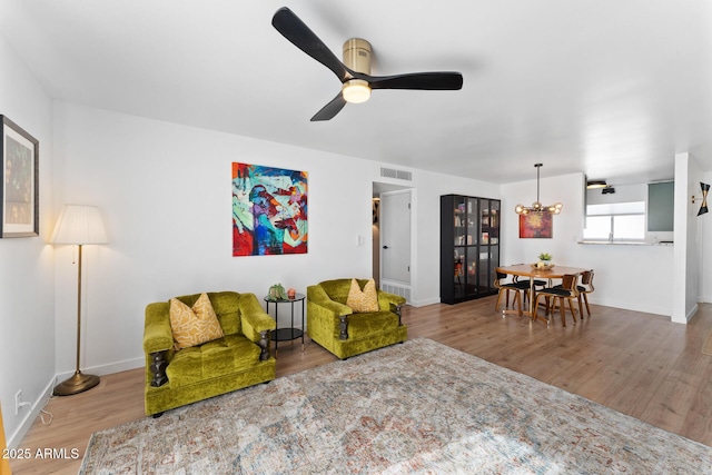 living room with ceiling fan with notable chandelier and wood-type flooring