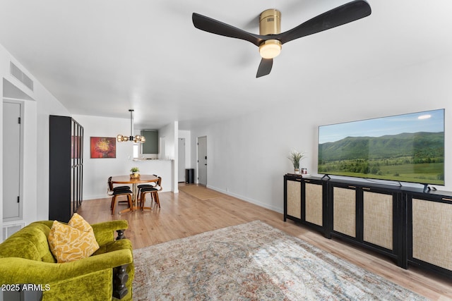 living room with ceiling fan with notable chandelier and hardwood / wood-style flooring