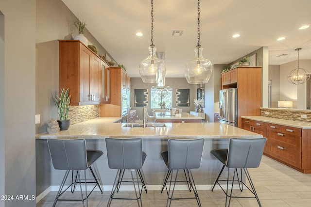 kitchen with pendant lighting, stainless steel fridge, tasteful backsplash, kitchen peninsula, and a breakfast bar area