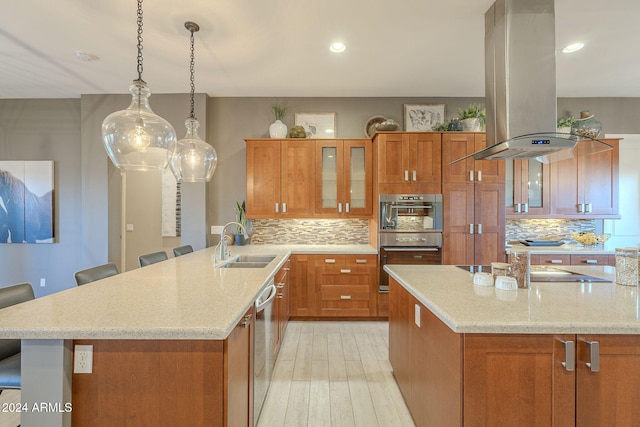 kitchen with a kitchen bar, appliances with stainless steel finishes, island exhaust hood, tasteful backsplash, and sink