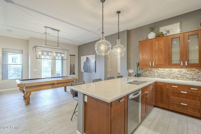 kitchen featuring backsplash, sink, dishwasher, a breakfast bar area, and pool table