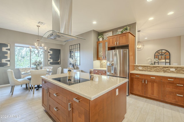 kitchen featuring black electric stovetop, backsplash, island range hood, stainless steel fridge with ice dispenser, and hanging light fixtures