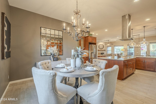 dining space featuring ceiling fan with notable chandelier, light wood-type flooring, and sink