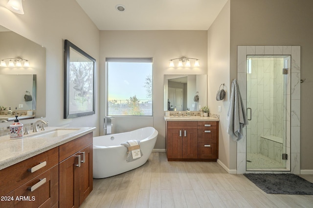 bathroom with hardwood / wood-style flooring, vanity, and plus walk in shower