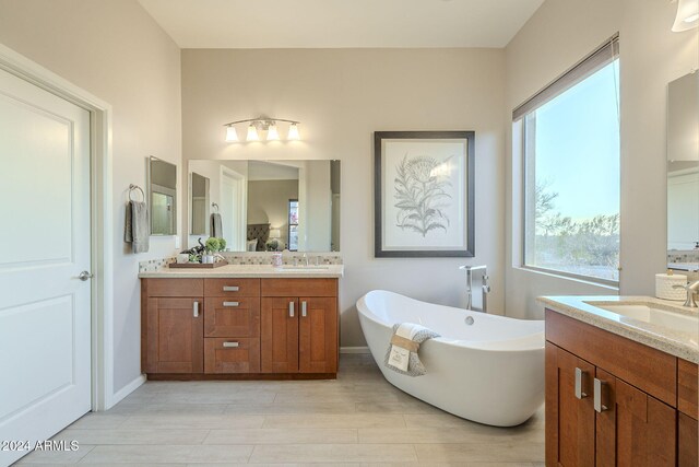 bathroom with a bathing tub, a wealth of natural light, vanity, and wood-type flooring