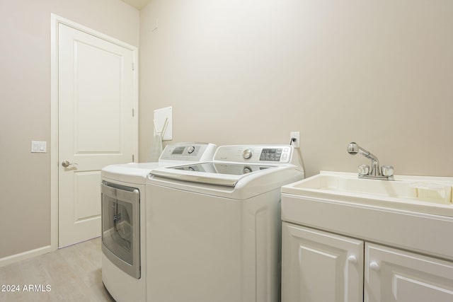 laundry room featuring cabinets, light wood-type flooring, and washing machine and clothes dryer