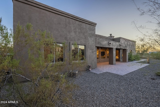 back house at dusk featuring a patio area