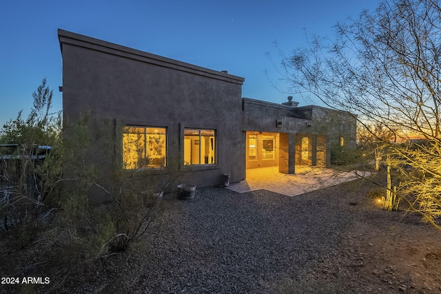 back house at dusk featuring a patio area